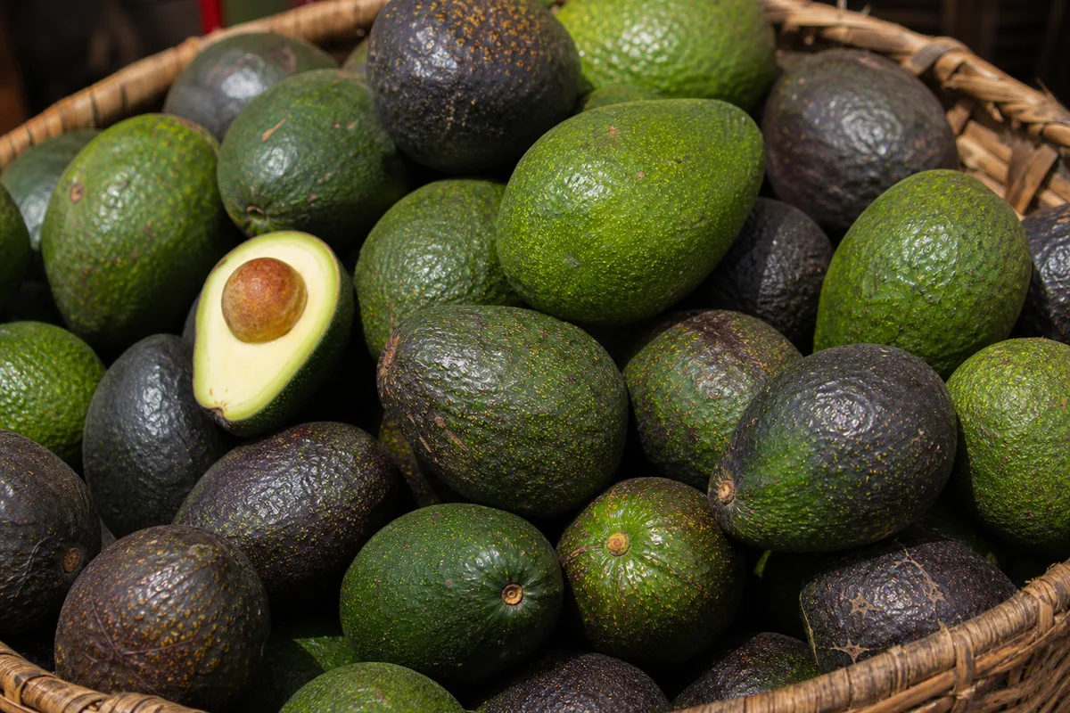 Ripe avocados piled in a woven market basket